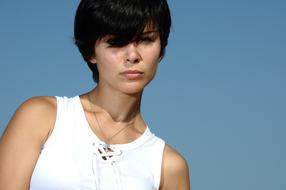 Portrait of the girl with short hair, in white dress, at blue sky on background