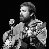 Black and white portrait of the artist, singing and playing on the guitar