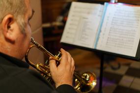 senior man plays horn in front of musical sheets