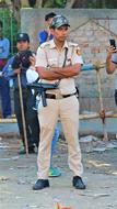 Police constable standing, among the other people, near the wall