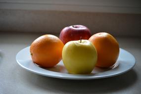 colored apples and oranges on a plate