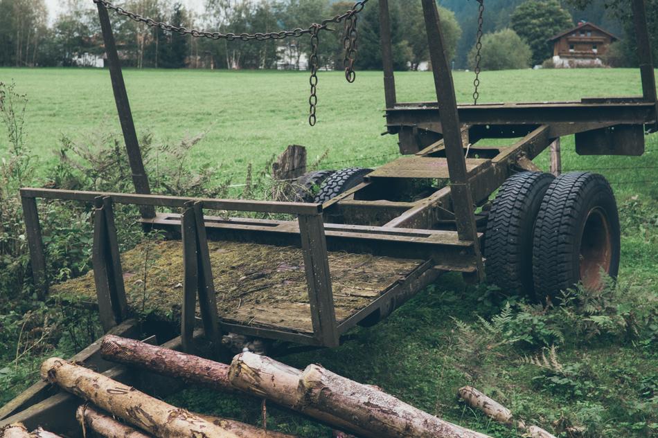 an old car with logs in the green grass