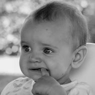 Black and white portrait of the cute child girl, with the finger in the mouth