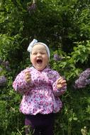 happy child among the bushes with purple flowers