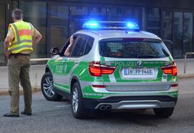 Man in yellow vast stands near Police car, germany, hamburg