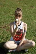 young Girl sits on lawn eating Ice cream