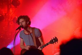 singer with guitar on stage in red light