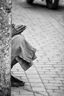 Black and white photo of senior Man sits on roadside