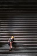 Man in hat, sitting on the stairs, in light and shadow