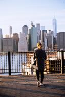 a girl stands near the railing against the backdrop of skyscrapers