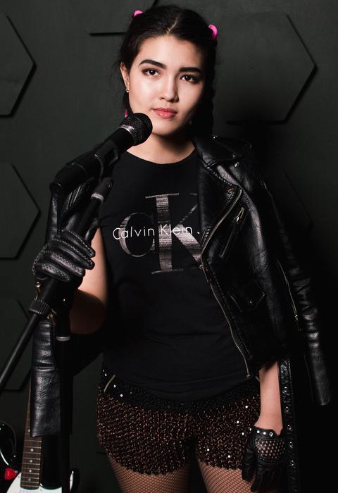 Girl in dark clothing, near the microphone, in light