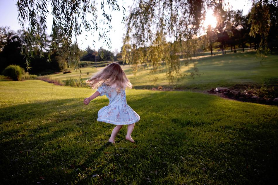 girl in a blue dress is spinning on the field