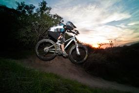 Extreme sport, boy riding bicycle in wilderness at dusk