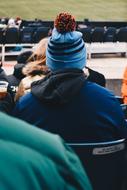 Back view of the guy in colorful beanie, sitting among the other people