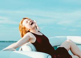 Happy redhead Girl sits on sofa