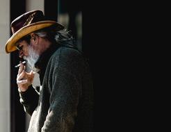 old bearded man with a cigarette on a city street