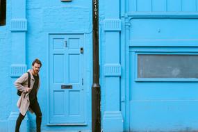 photo of a man with a backpack on the background of a blue building