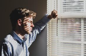 Guy, looking in the window, with sunlight, with the shutters