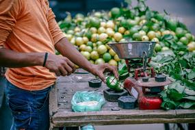 Man, cutting fruits on the table, on the market