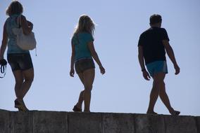 People, walking in sunlight, under the blue sky