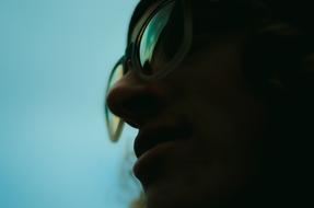 Silhouette of a man, with the colorful, shiny eyewear, at turquoise sky on background