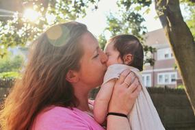 mother kissing her baby daughter outdoor