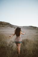 girl walks through the pasture in the mountains