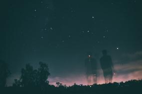 Silhouettes of the people, on the beautiful landscape, under the colorful and beautiful sky, at the night