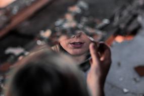 girl paints her lips near the mirror