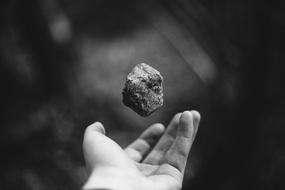 Black and white photo with the rock, falling on the hand of the guy
