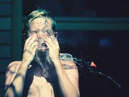 boy under running water close-up