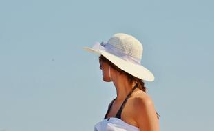 photo portrait of a girl in a white hat against a blue sky