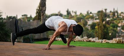 Itamar Kazir in hat, doing street workout, among the colorful plants and rocks