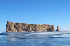 a rocky cliff with blue water and blue sky