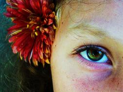 Close-up of the beautiful, green eye of the girl, with the colorful flower