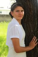 girl in white posing near a tree