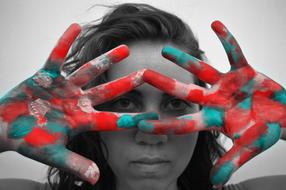 girl with bright Painted Hands in front of face