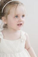 Portrait of the cute, blonde child girl, with the headband, and in white dress