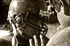 monochrome photo of a conversation between an American football player and a coach