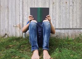 Young Person Reading book at wooden wall