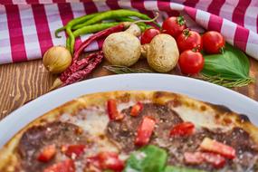 pizza with sausage, mushrooms and tomatoes on the table