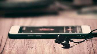 Music, smartphone and Headphone on wooden surface