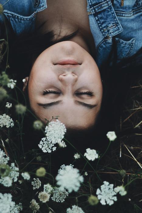 Portrait of the girl, laying upside down, among the colorful and beautiful flowers