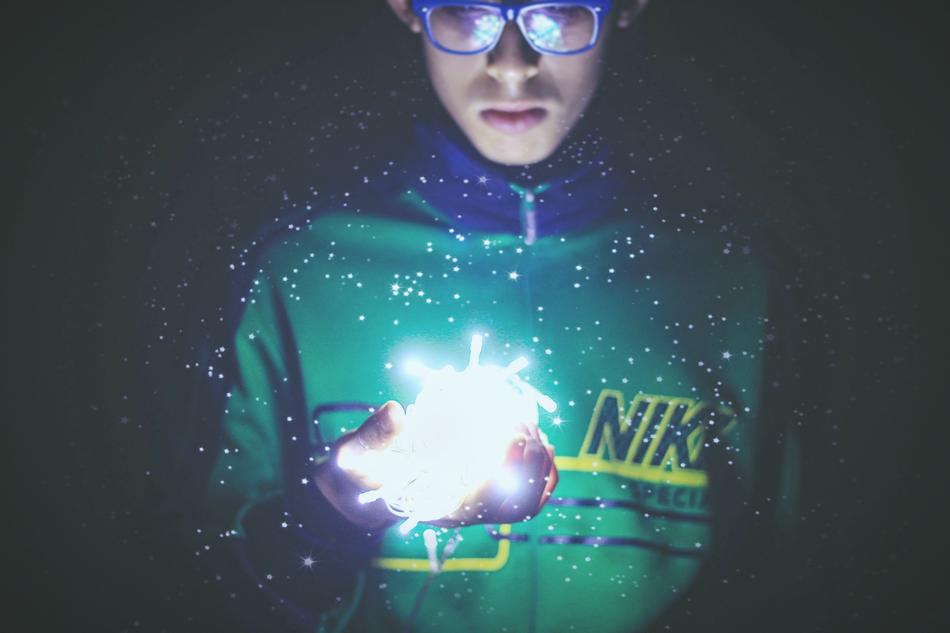 boy with glasses looks at the christmas lights on his hand