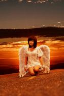 girl with white wings against the background of an orange sunset