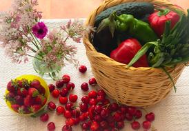 berries on table and ripe vegetables in basket