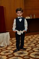 child Boy in bow tie stands on mosaic floor