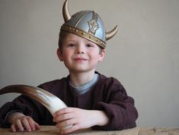 photo of a boy in a viking helmet with a horn in his hand