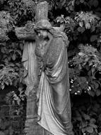monochrome photo of a woman and a cross in a cemetery