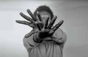 Man with hands stretched out in front of face, blur grey background